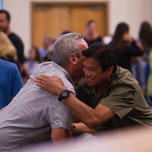 two men friends embracing in crowd